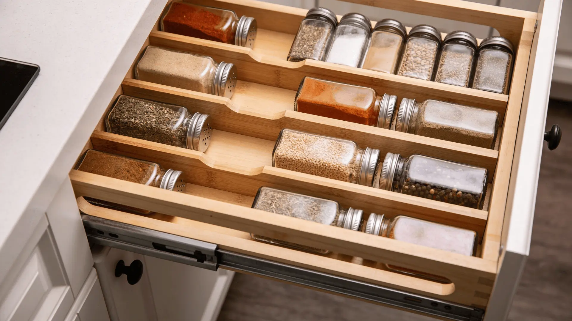 Drawer with tiered spice organizer showing jars arranged in stepped rows for easy viewing