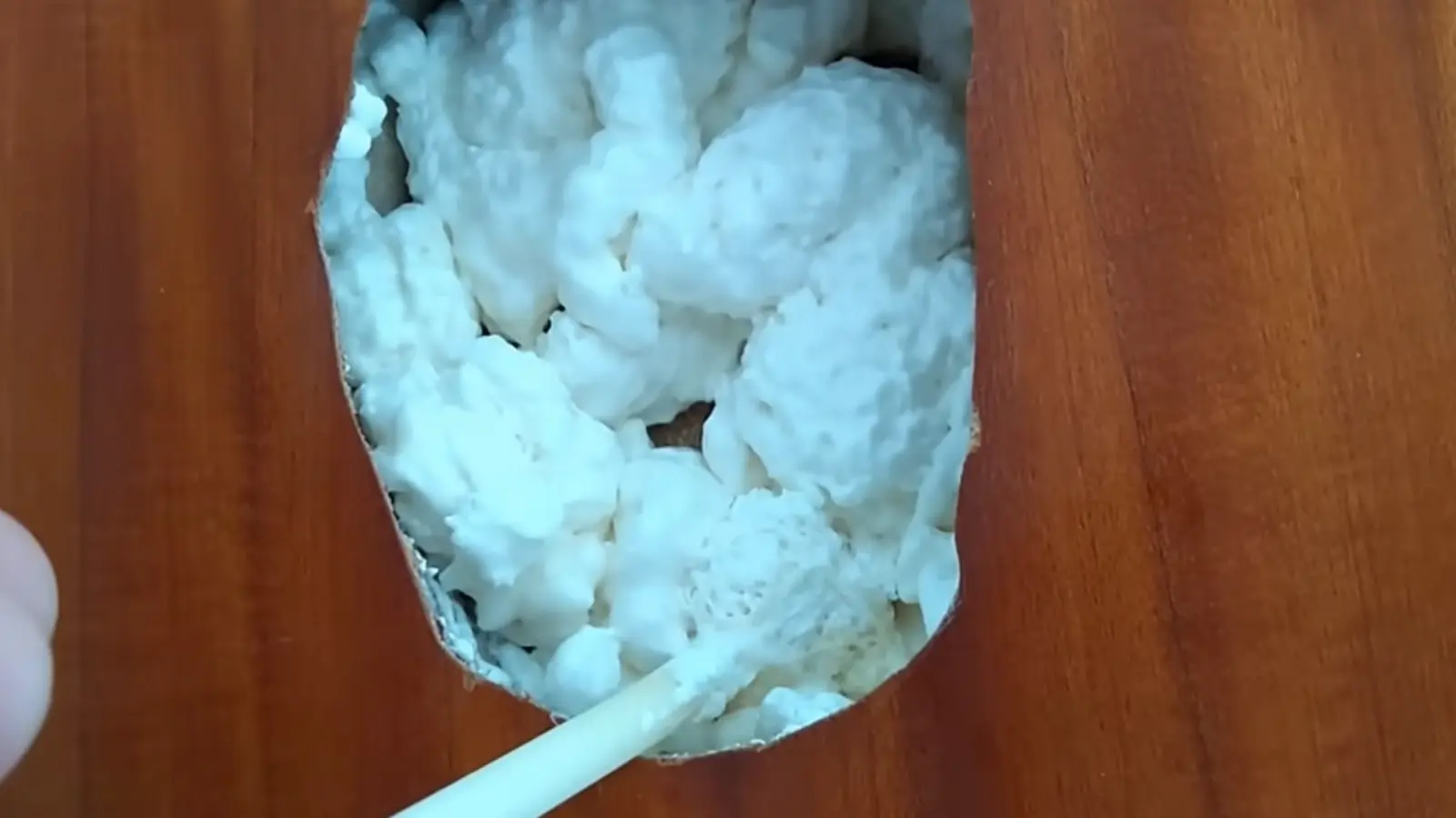 Expanding foam being applied into a hole in a door