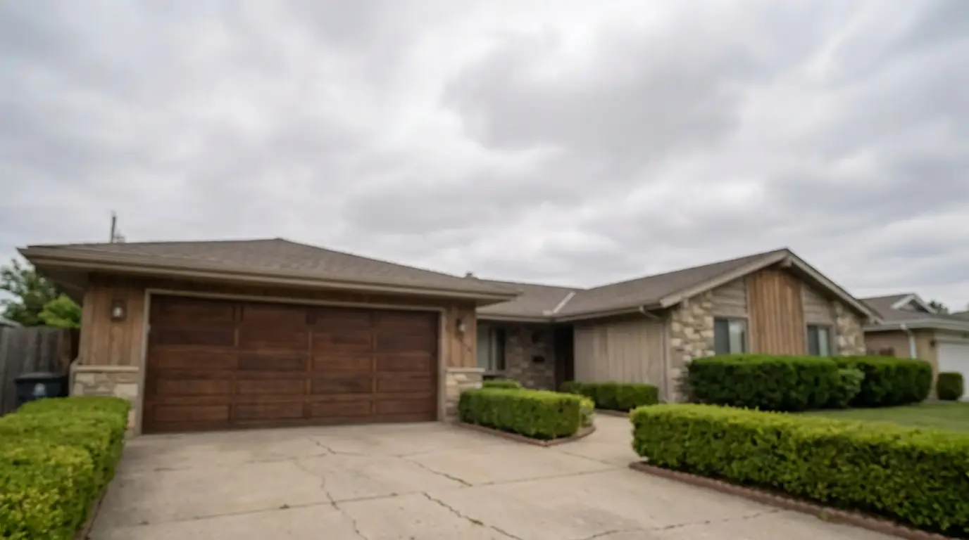 Single-story suburban house with wooden garage door and stone accents under overcast sky