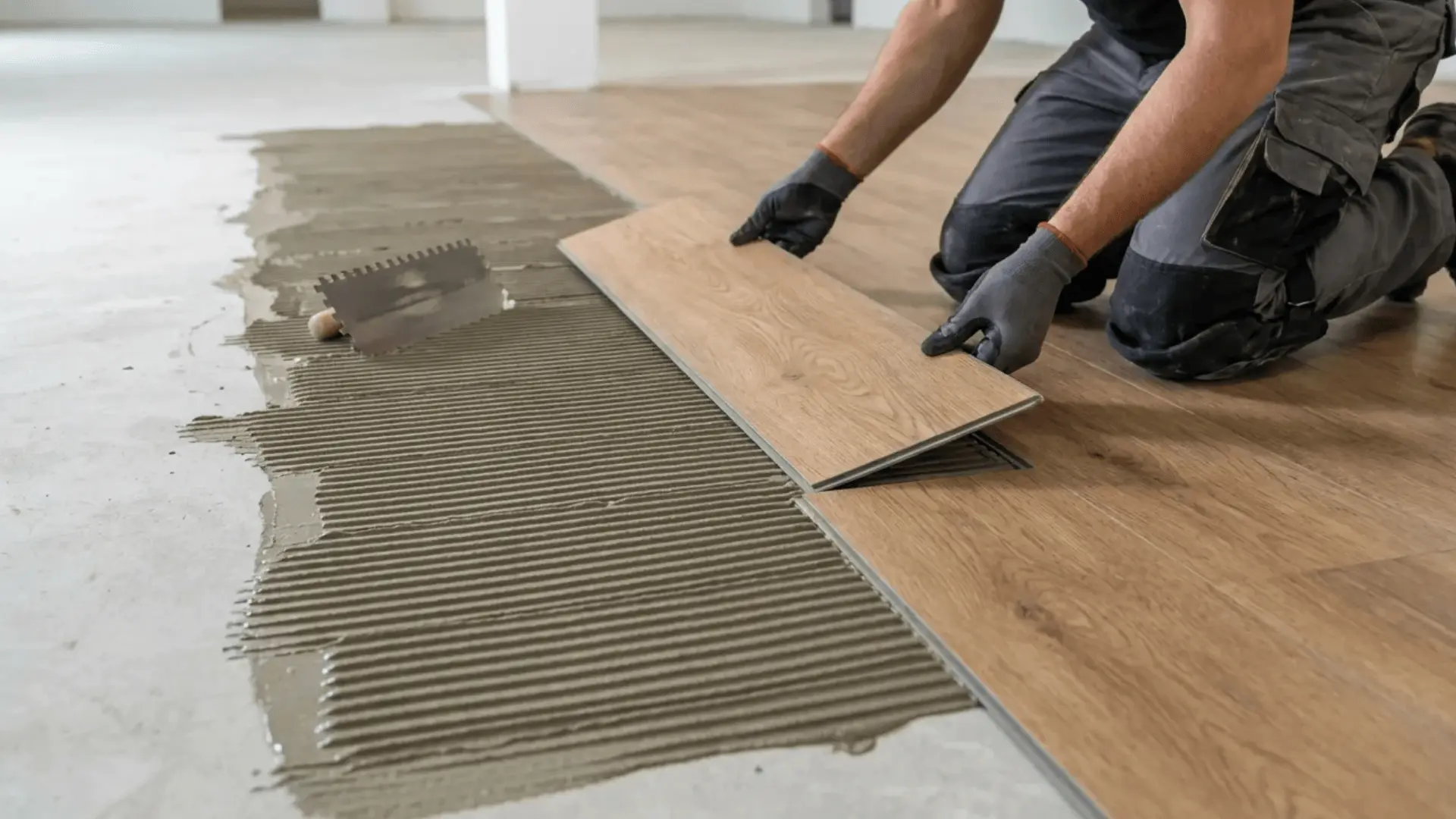 Installer placing luxury vinyl tile onto adhesive on a prepared subfloor.