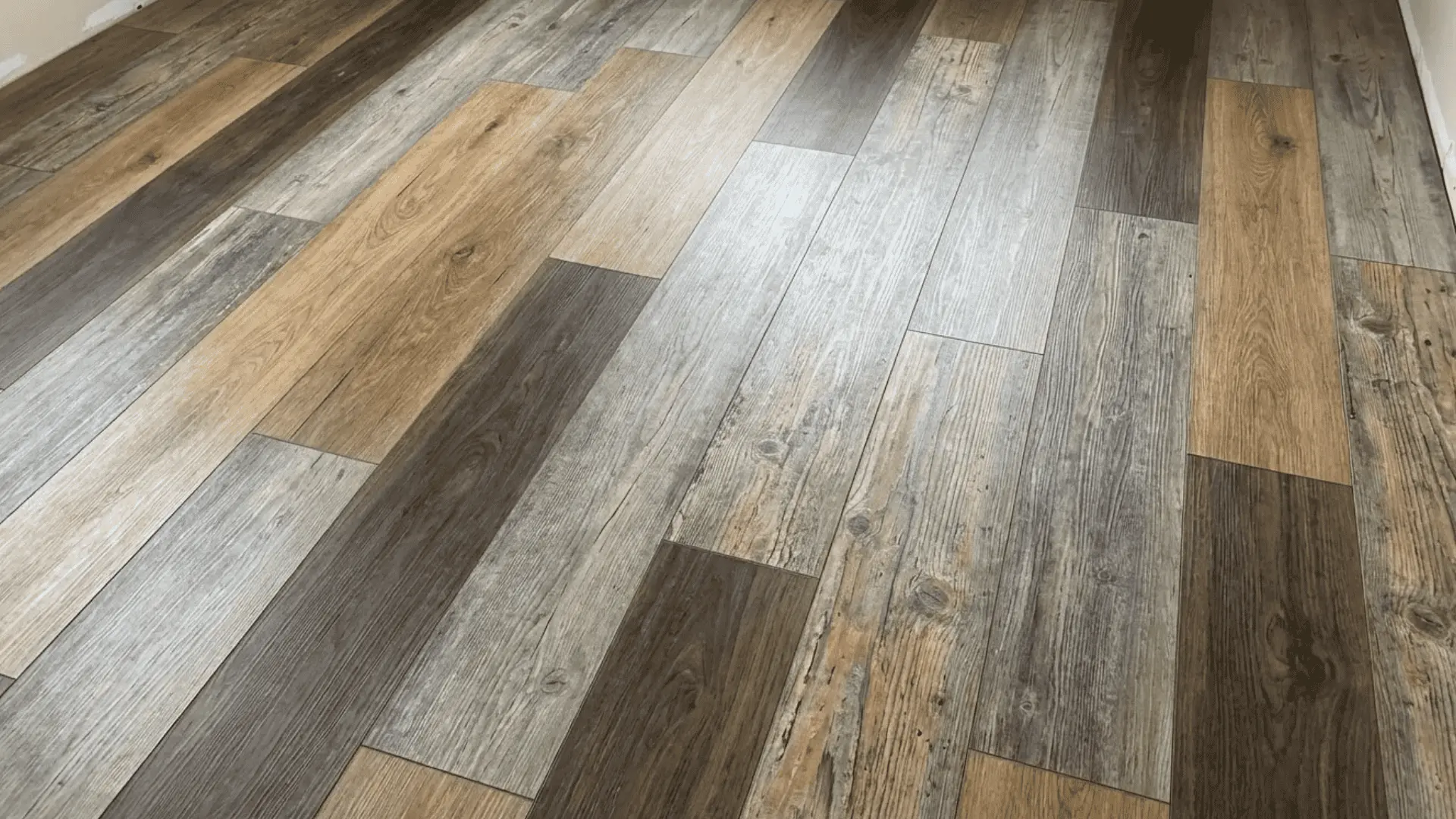 Luxury vinyl tile with oak, walnut, and rustic wood grain patterns installed in a wide plank floor layout.