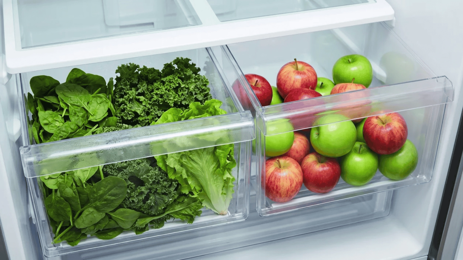 Open crisper drawers with greens in one and apples in another