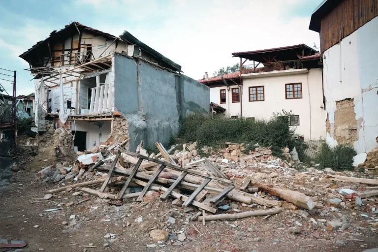 Partially collapsed building with debris and rubble in residential area under clear sky