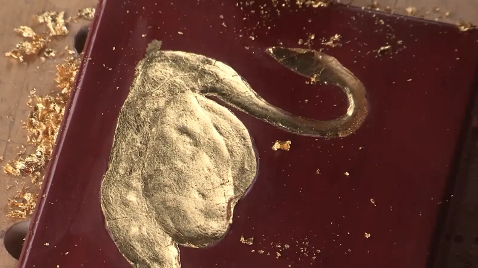 Soft cosmetic brush smoothing and evening out gold leaf for a clean and uniform finish