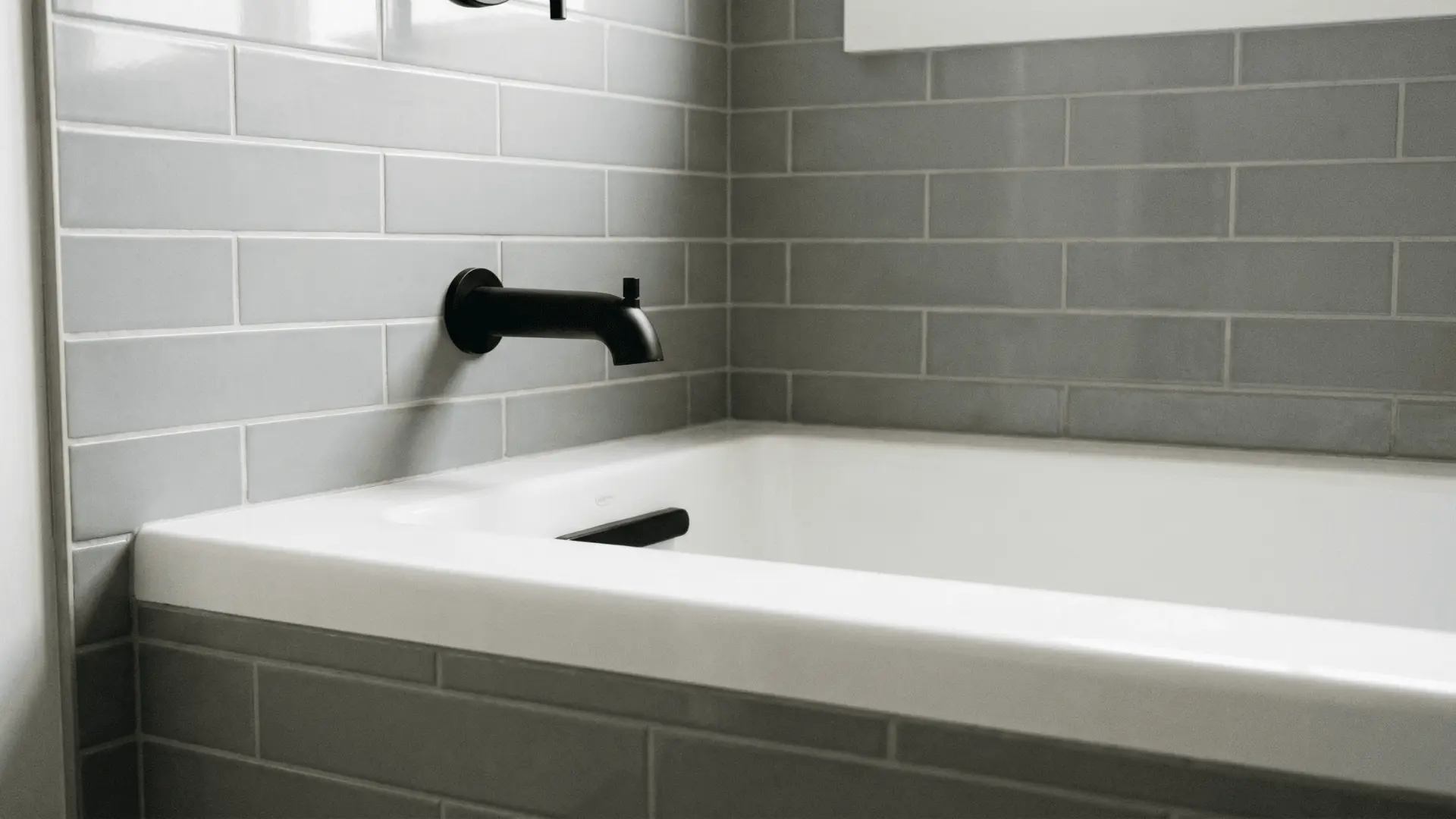 Tub spout mounted above bathtub rim with visible spacing on tiled wall