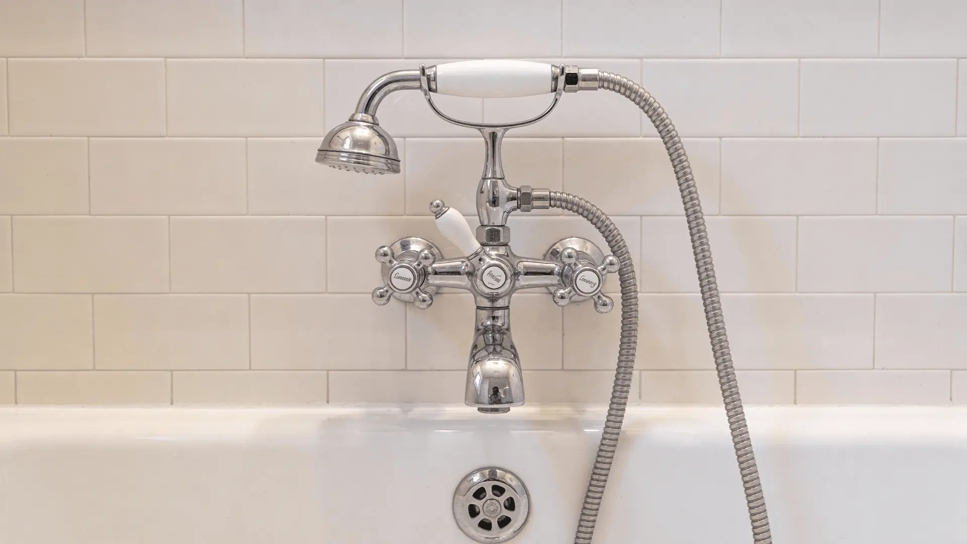 Wall-mounted tub spout and control valve aligned above a bathtub showing vertical spacing and placement