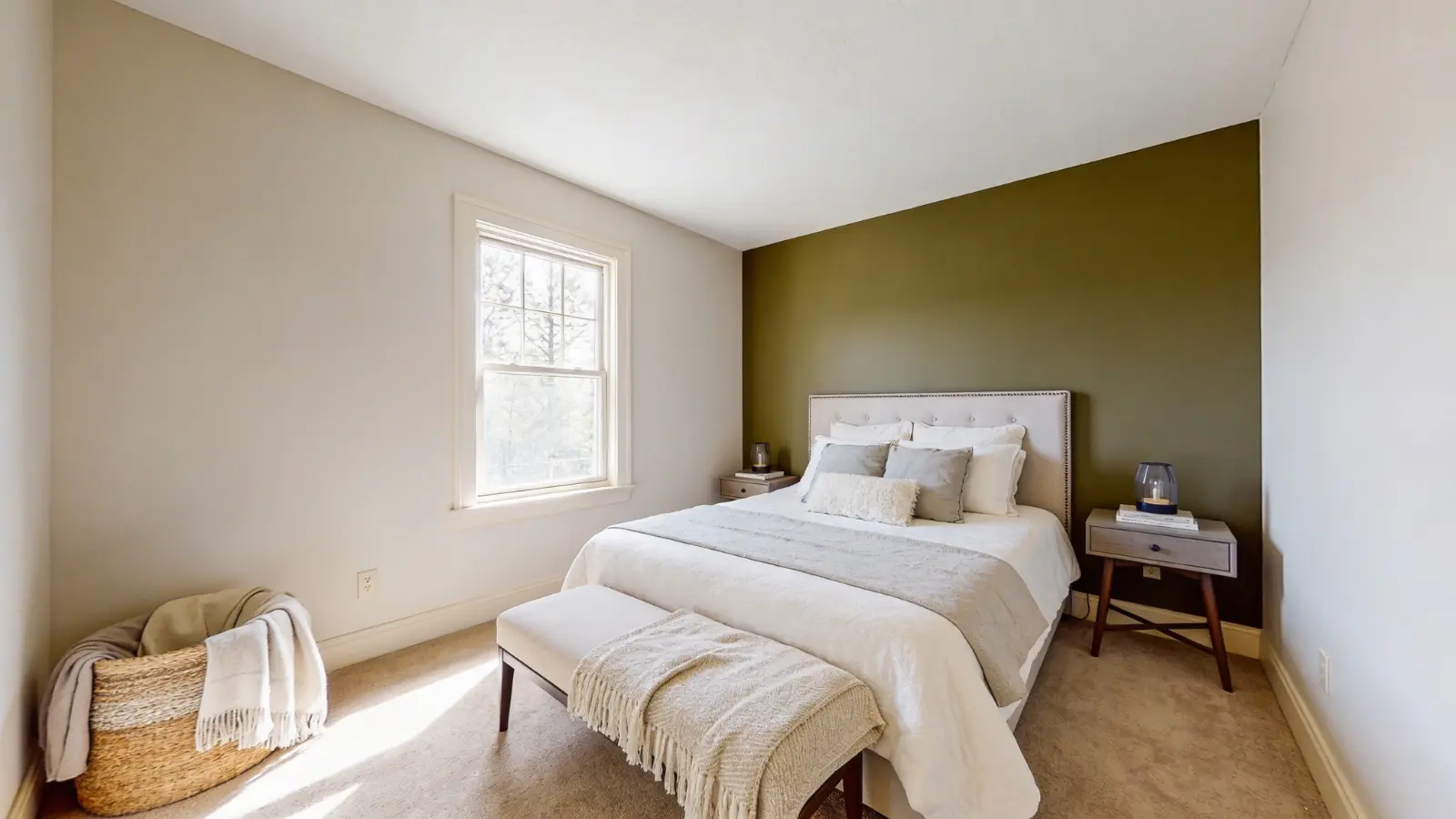 Wide view of bedroom with dark green accent wall, bed, and neutral walls (1)