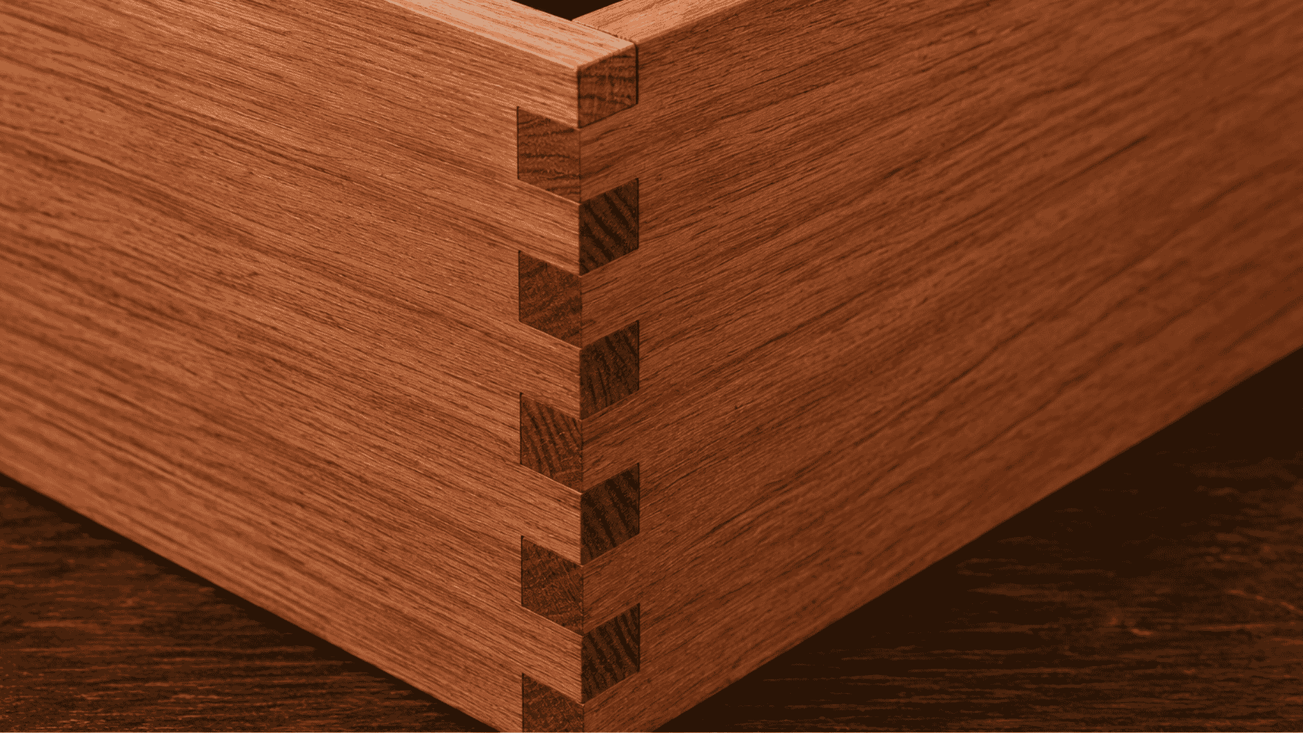 Close-up realistic box joint with square interlocking redwood finger joints on a dark wooden surface.