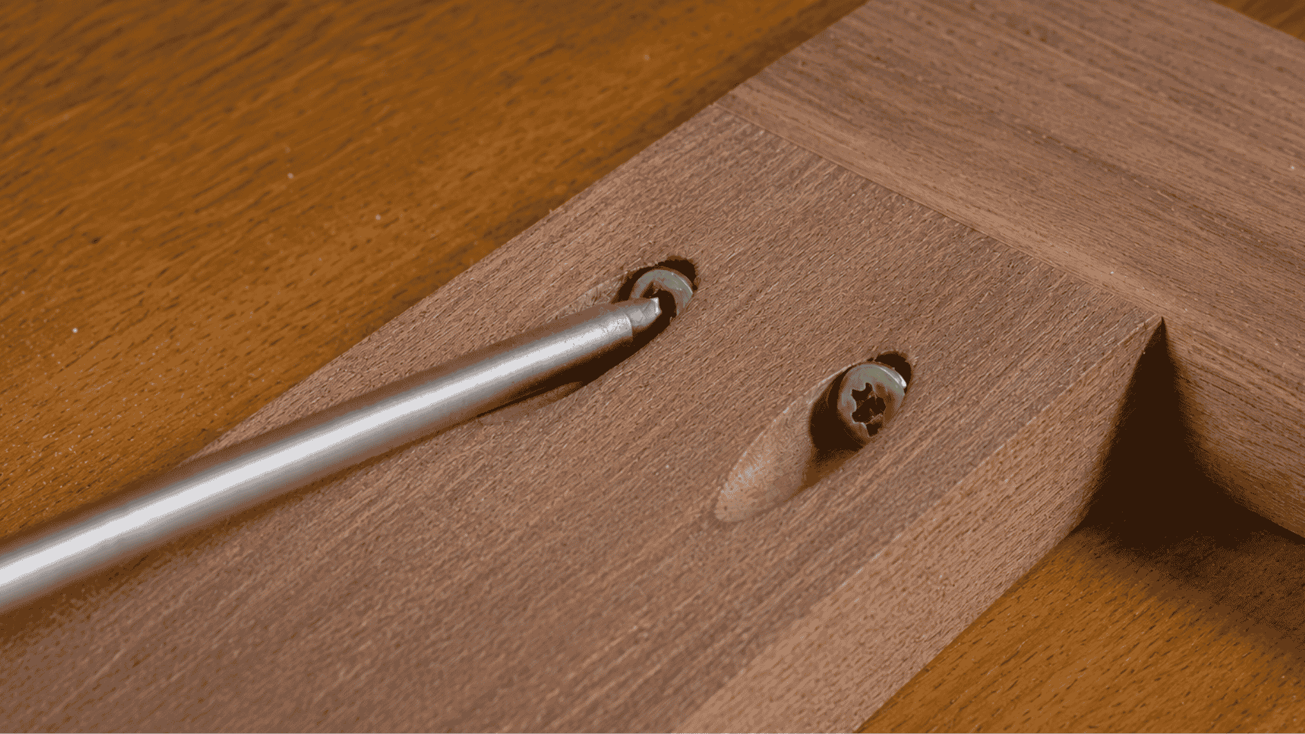 Realistic pocket hole joint with walnut wood boards connected using an angled screw hole on a brown background