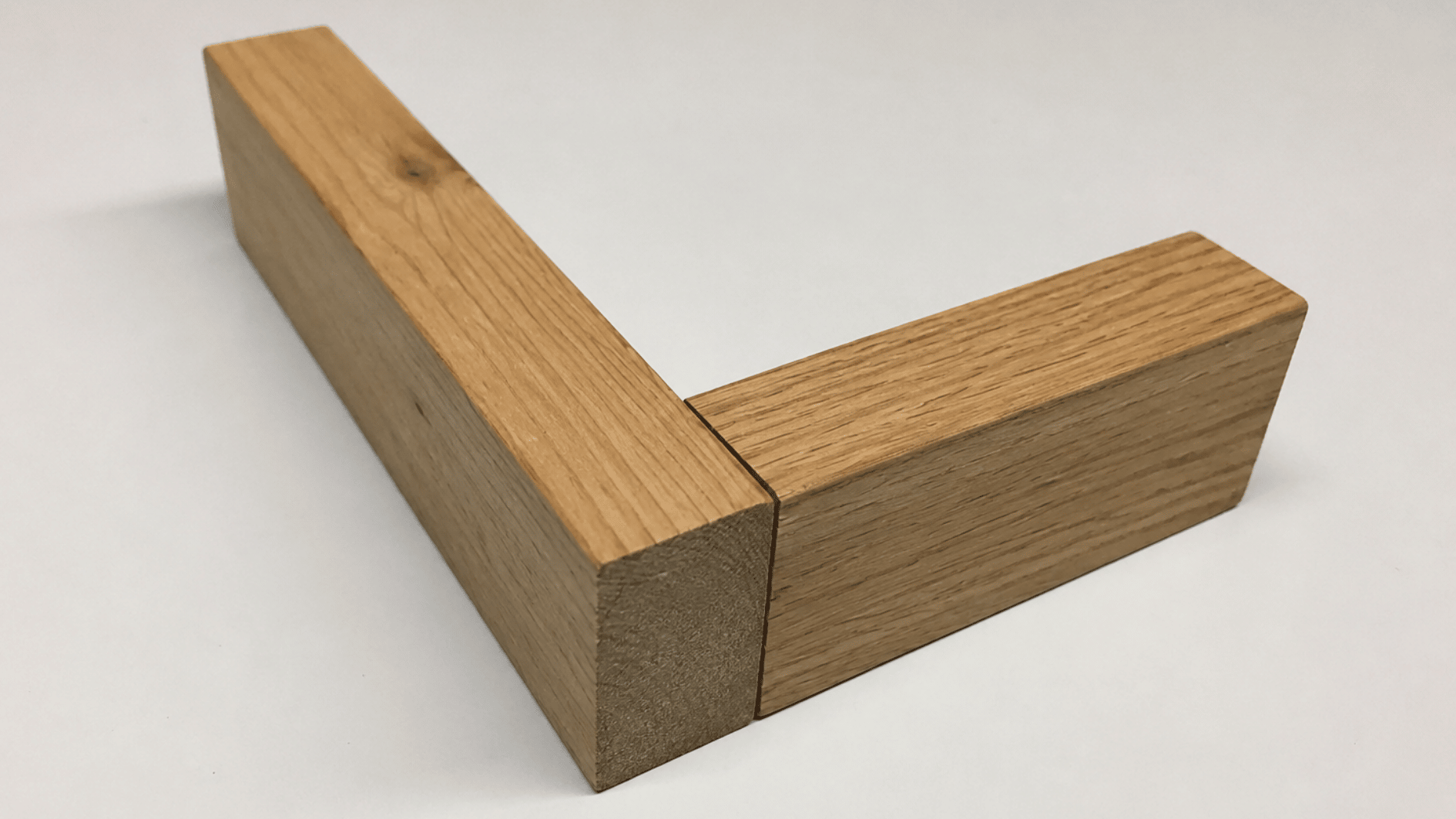 Wooden butt joint with two connected wood pieces placed on a white surface in a woodworking setup