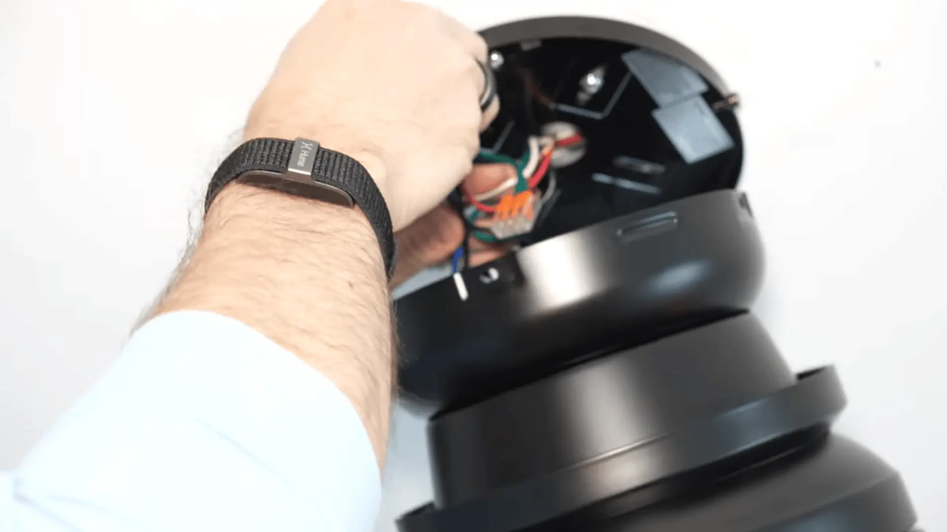 A person connecting wires in the ceiling fan's motor housing during installation.