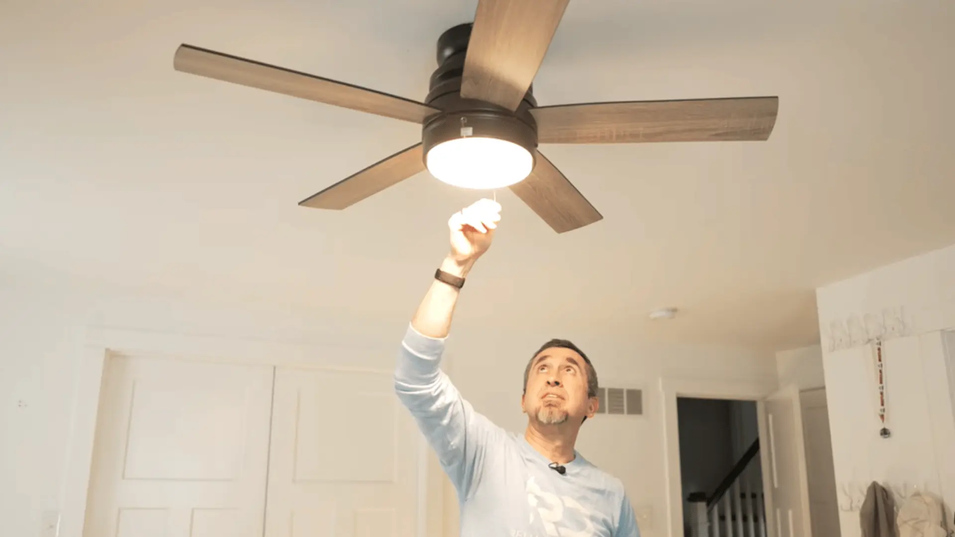 A person pulling the chain to test the functionality of a newly installed ceiling fan with a light