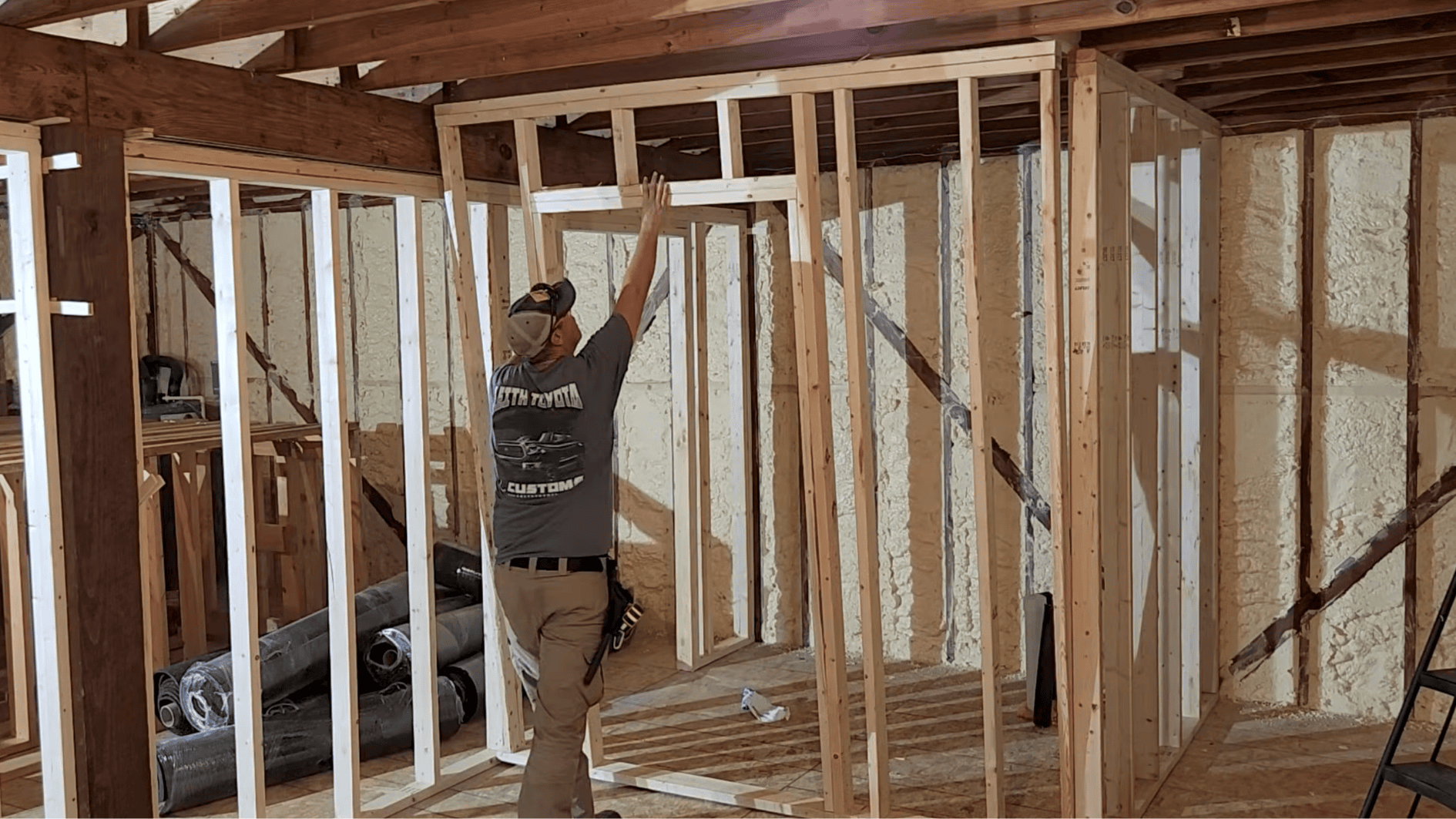 carpenter raising and positioning a newly framed interior wall with a door opening inside a house during wood stud wall construction