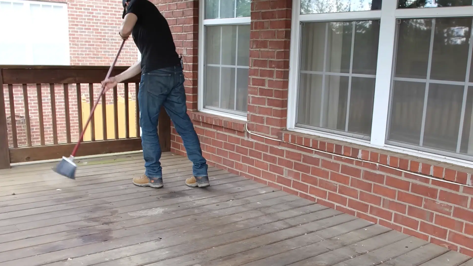 Deck cleared of furniture and plants, showing the use of a shop vac to clean debris between the deck boards.
