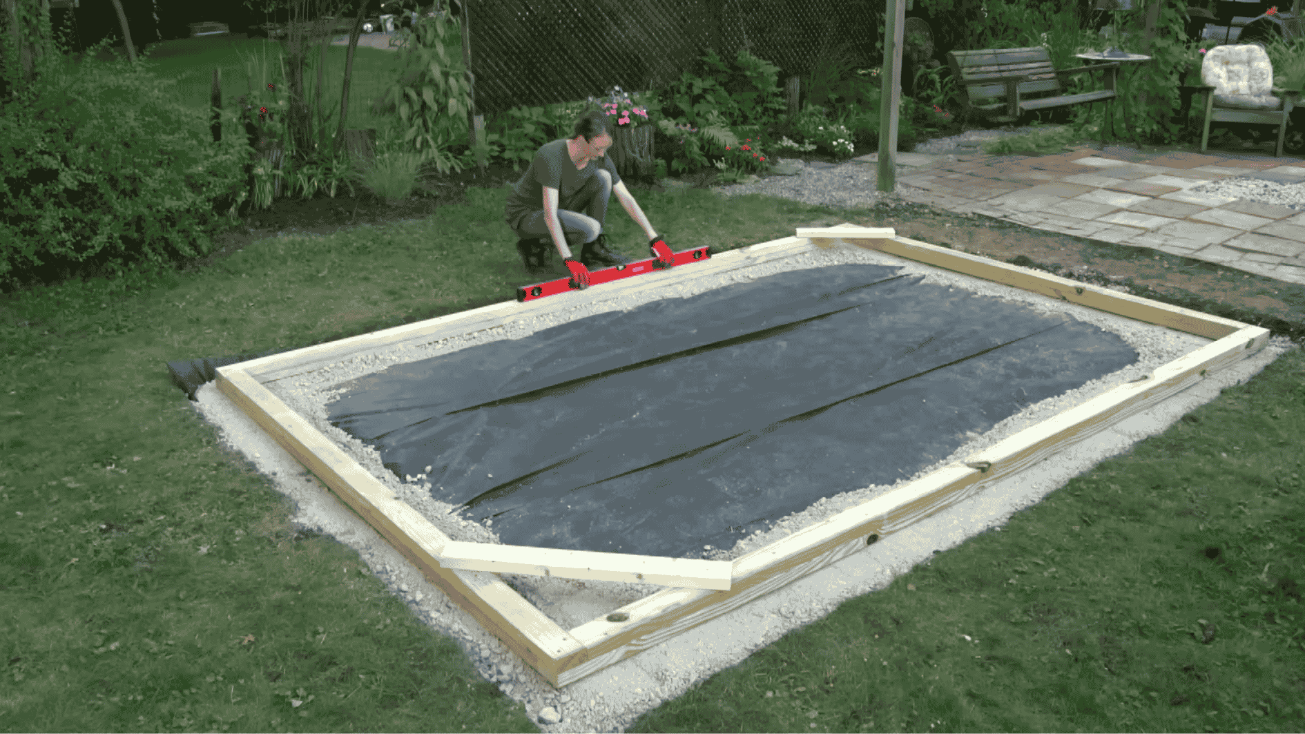 DIY greenhouse foundation setup with a leveled wooden base and concrete supports prepared for frame construction.