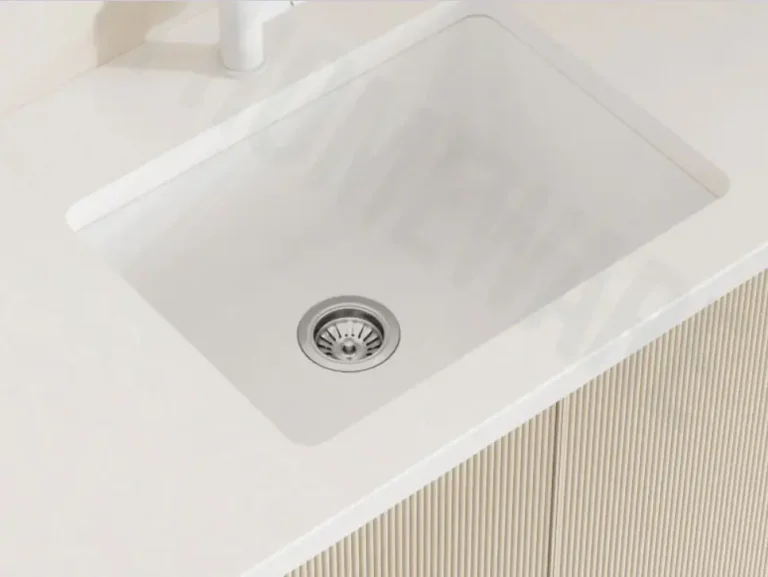 White kitchen sink with modern faucet on light-toned countertop