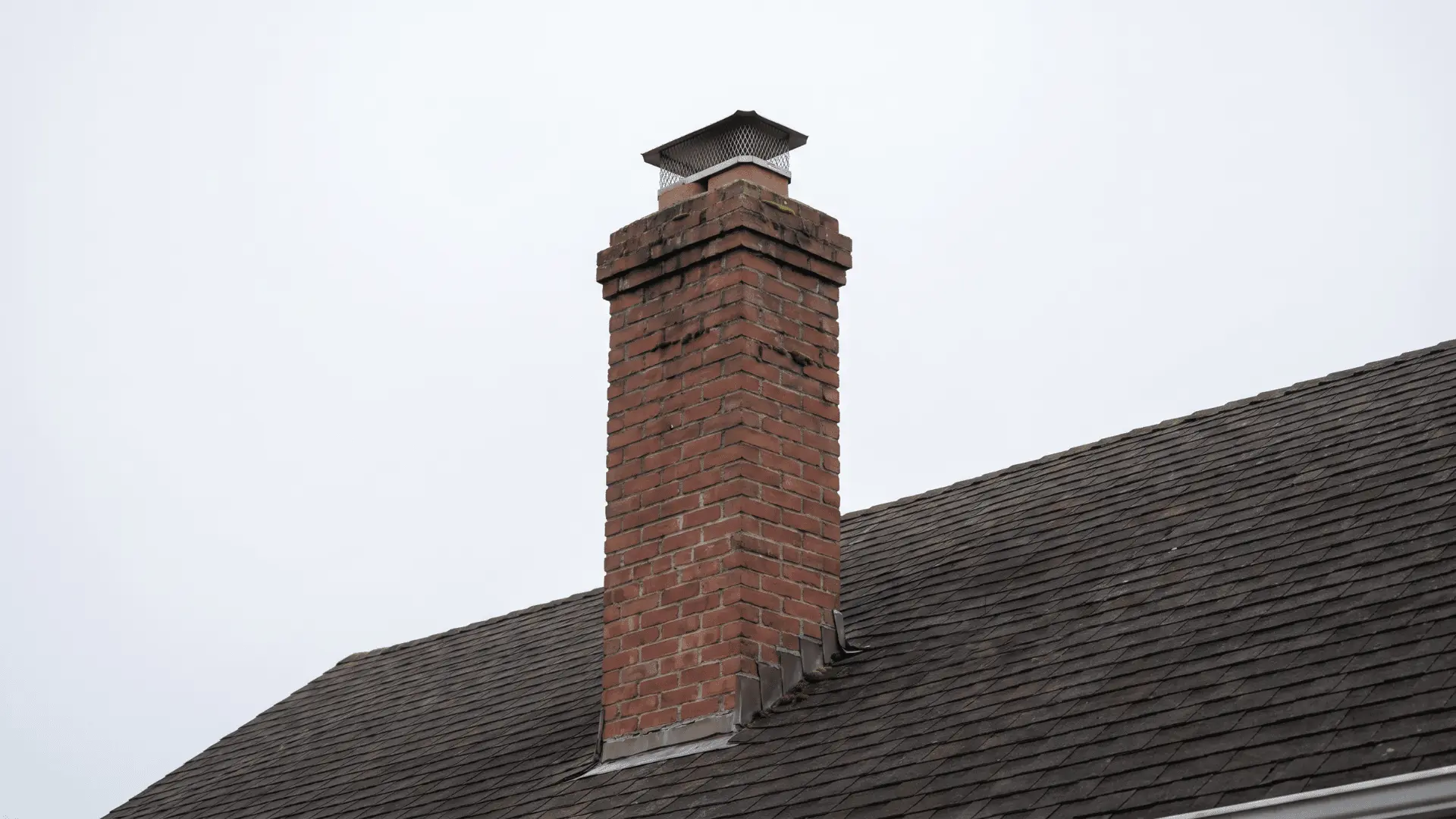 House chimney on rooftop with metal cap visible against sky