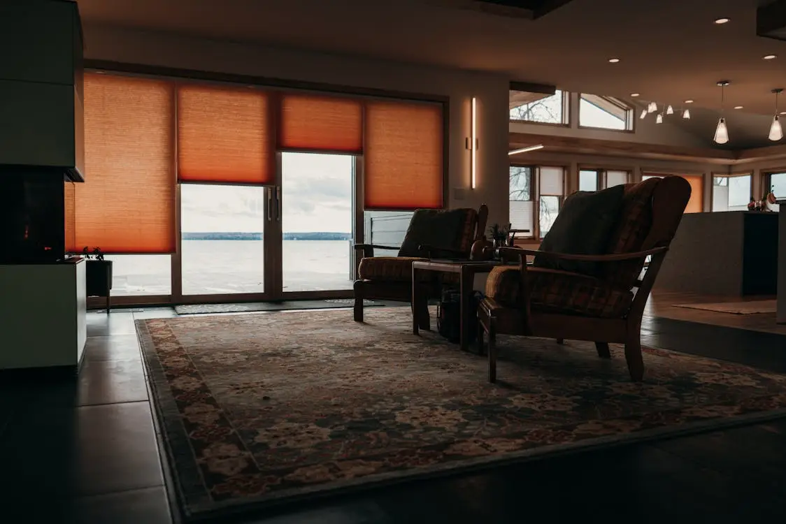 Cozy living room with armchairs facing large windows covered by orange blinds