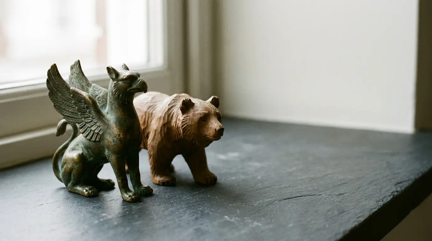 Small bronze griffin and wooden bear statues on windowsill with natural light