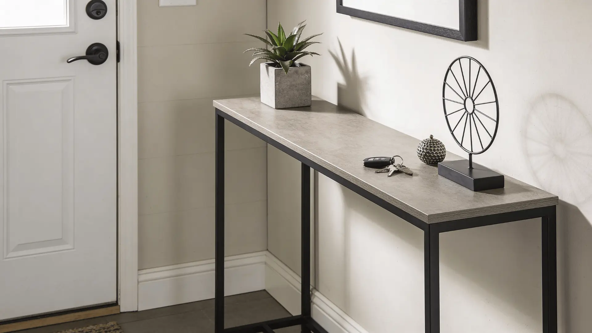 Narrow console table placed against a wall in an entryway with small items on top