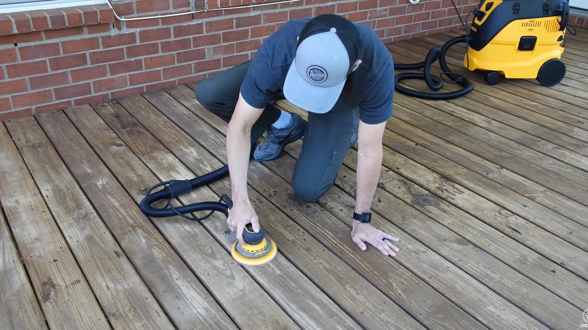 Orbital sander being used to sand stubborn stains on a deck, with a nail set driving raised nails below the deck surface.