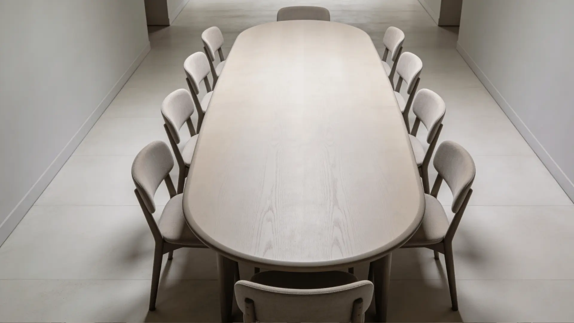 Oval dining table with rounded edges and chairs arranged evenly in a narrow room