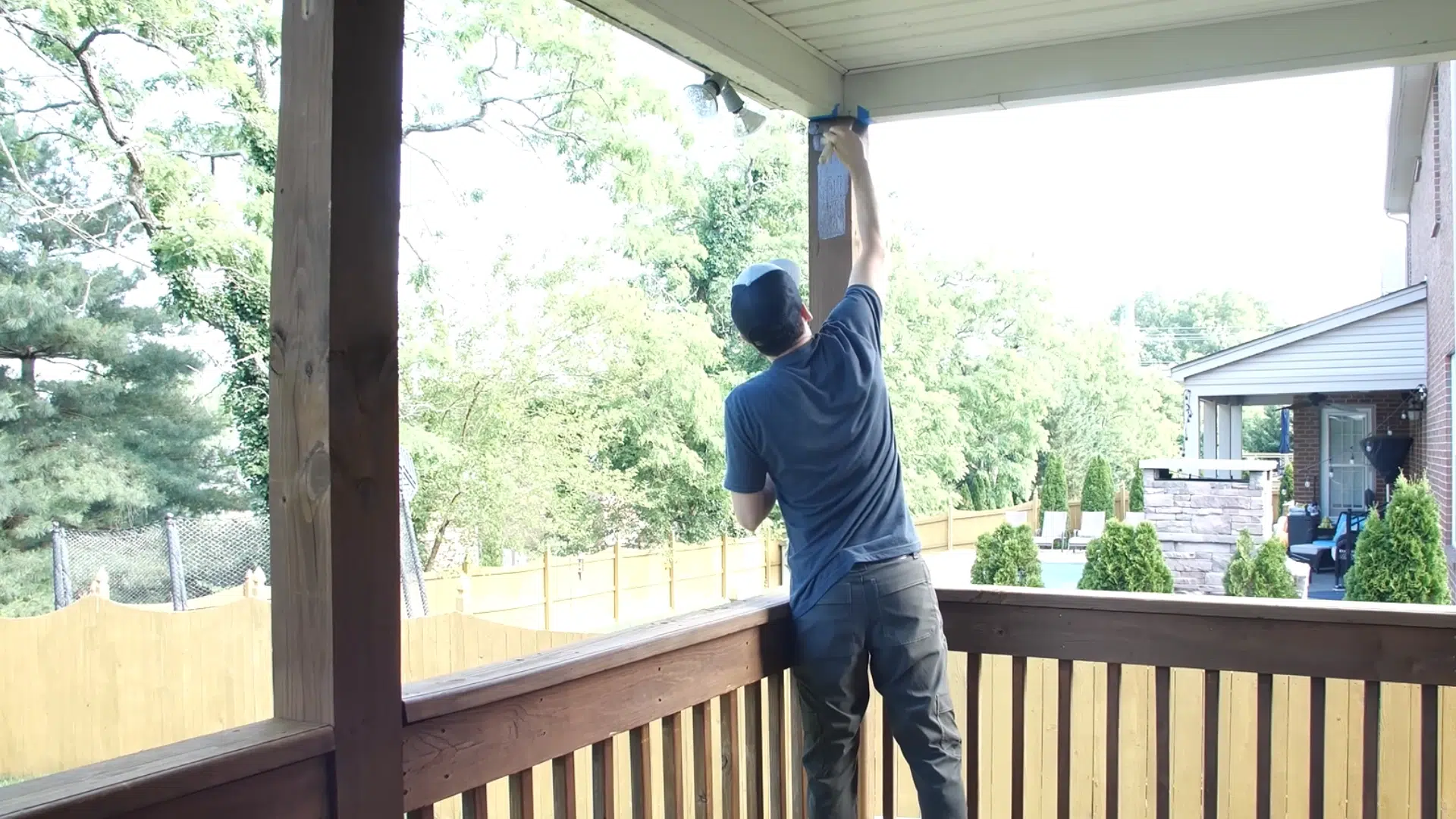 Person applying semi-transparent stain to the deck with a lamb’s wool applicator, using a brush to touch up edges and missed spots.