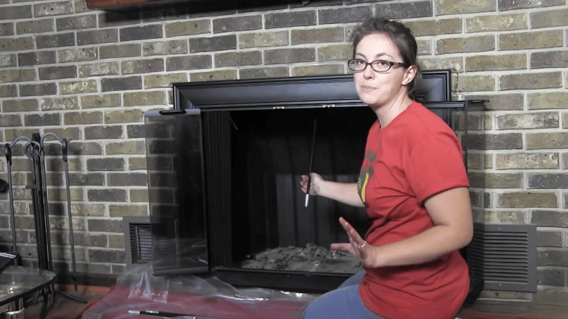 Person inserting chimney brush rod through fireplace damper into flue to begin cleaning from inside