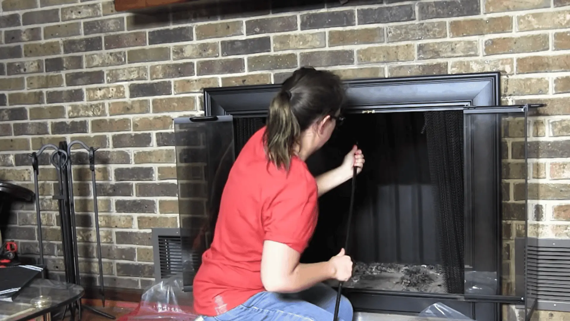 Person pushing chimney brush rods upward inside fireplace, scrubbing flue walls to remove soot and creosote