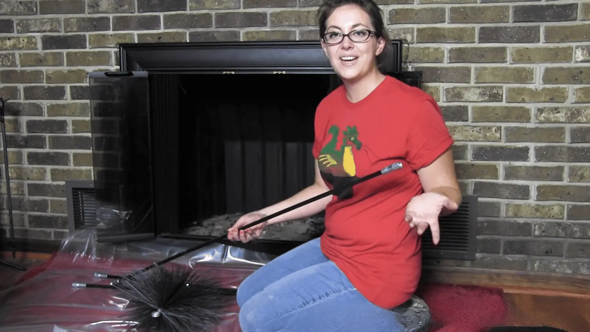 Person sitting by fireplace holding chimney brush and rods, preparing tools for cleaning chimney from inside