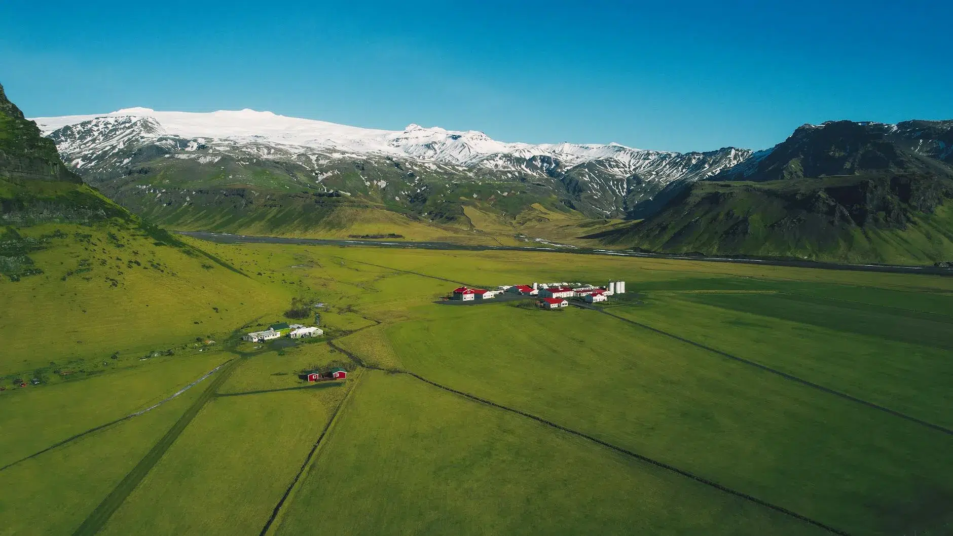 Aerial view of lush meadows and snow-capped mountains in Rangárþing eystra, Iceland.