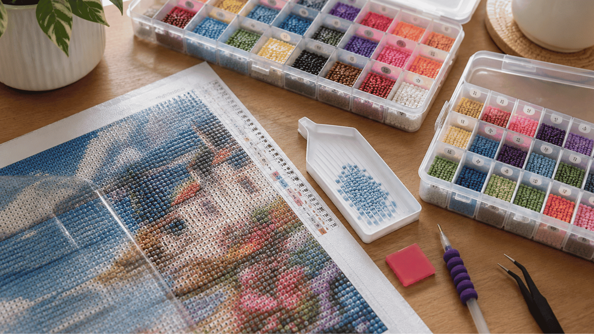 realistic diamond painting setup on a wooden desk with colorful resin diamonds, partially completed canvas, applicator pen, tray, wax pad, tweezers, and storage containers under soft natural light