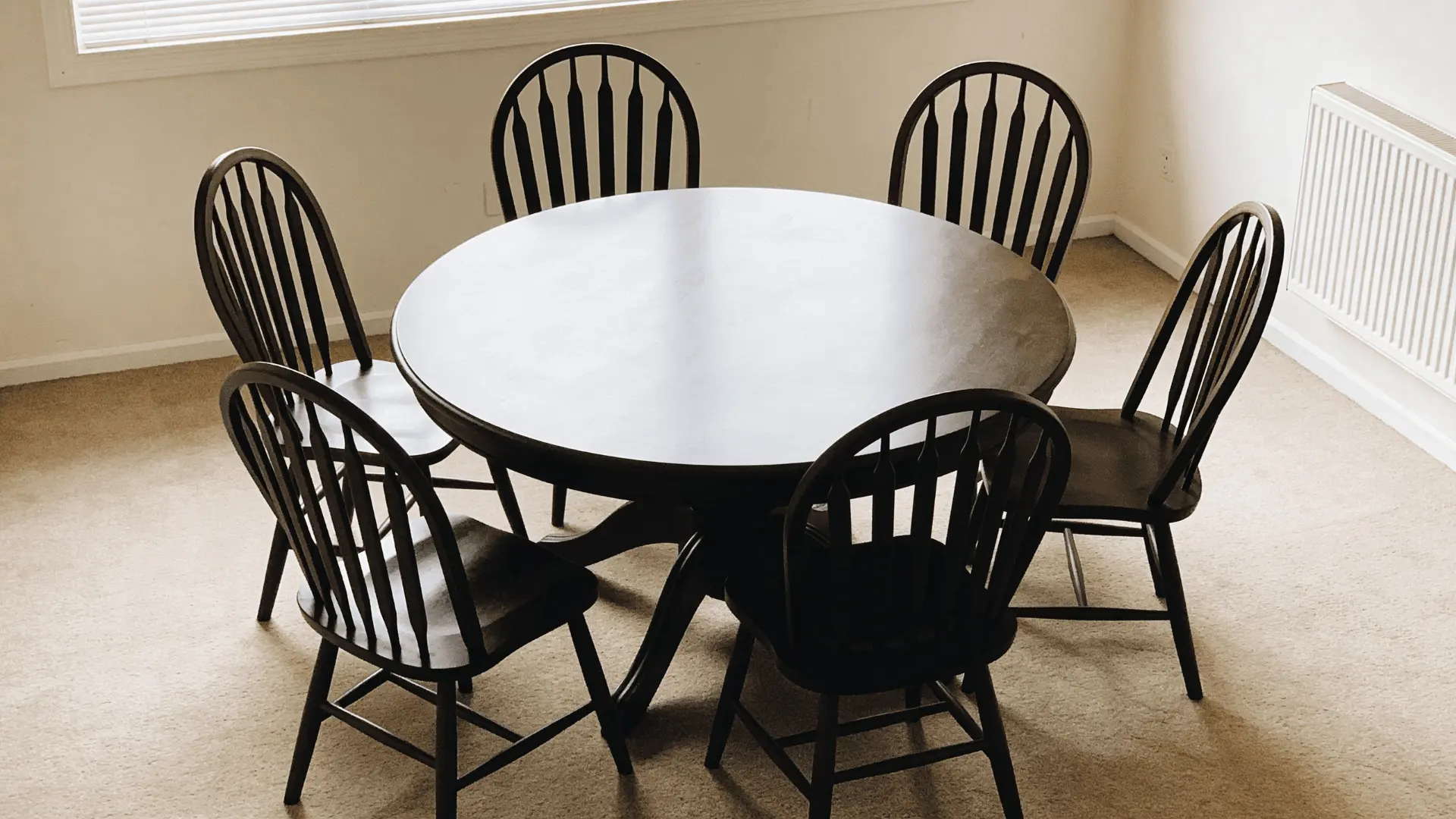 Round table with chairs placed evenly around it in a compact room