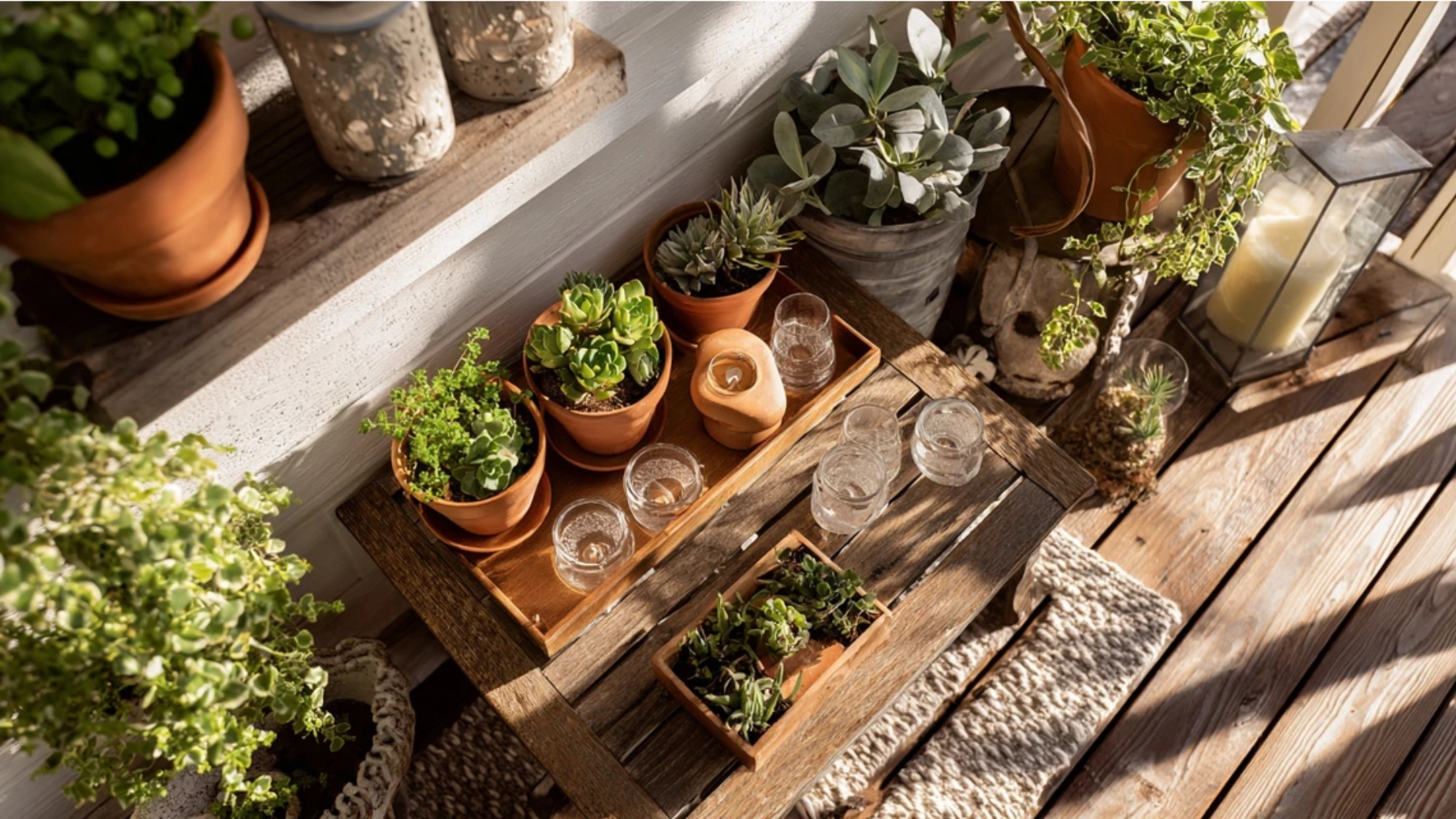 screened porch corner with DIY decor including hand painted terracotta pots trailing plants a rustic floating shelf with candles and a repurposed wooden drink station