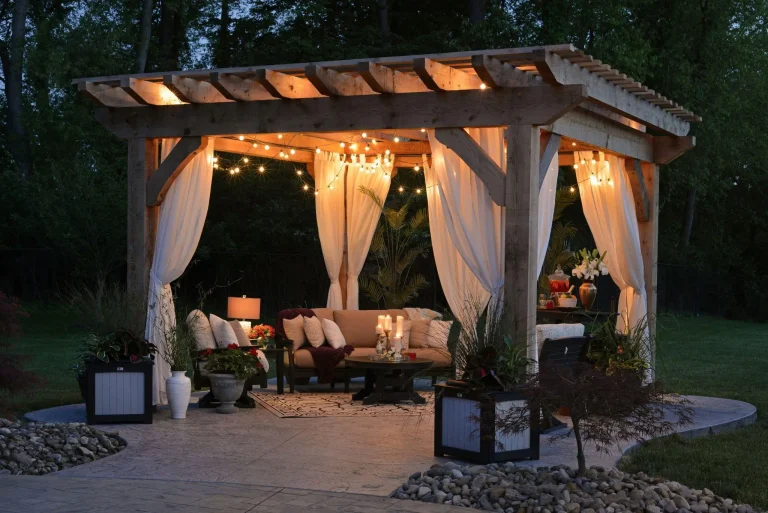 Cozy outdoor gazebo with string lights and draped fabric, featuring a sofa and potted plants