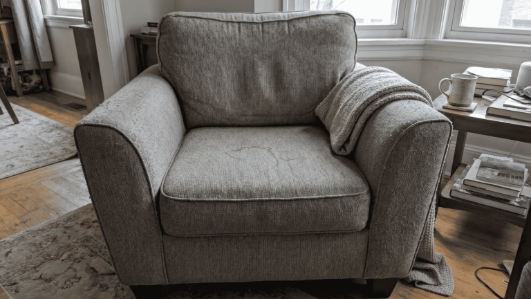 Upholstered chair with light stain and minor surface marks in a home setting