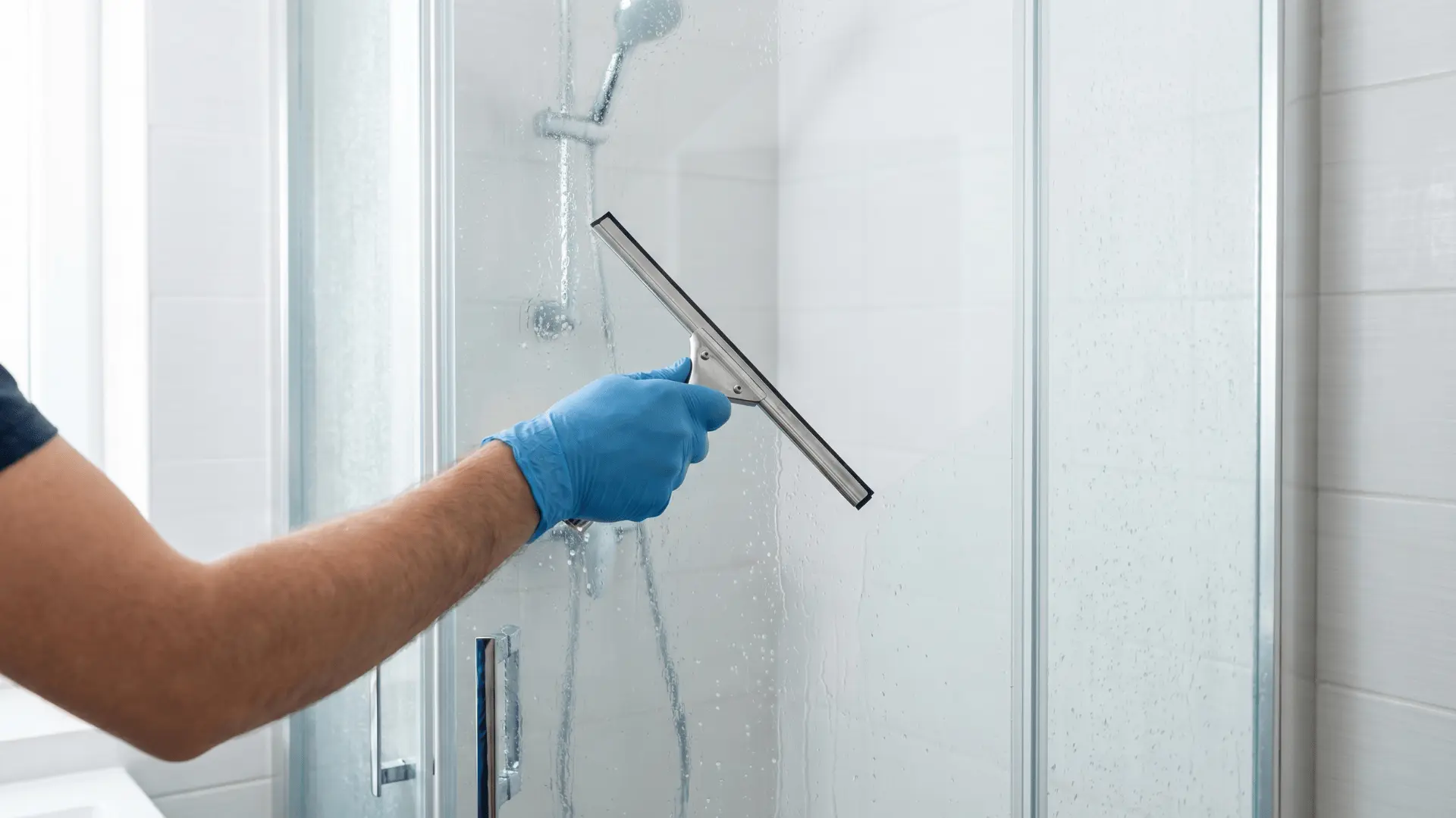 Using squeegee to keep shower glass clean
