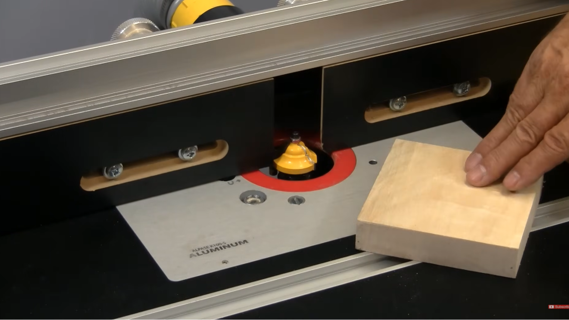 wood piece placed beside router bit on a woodworking router table with fence guide setup
