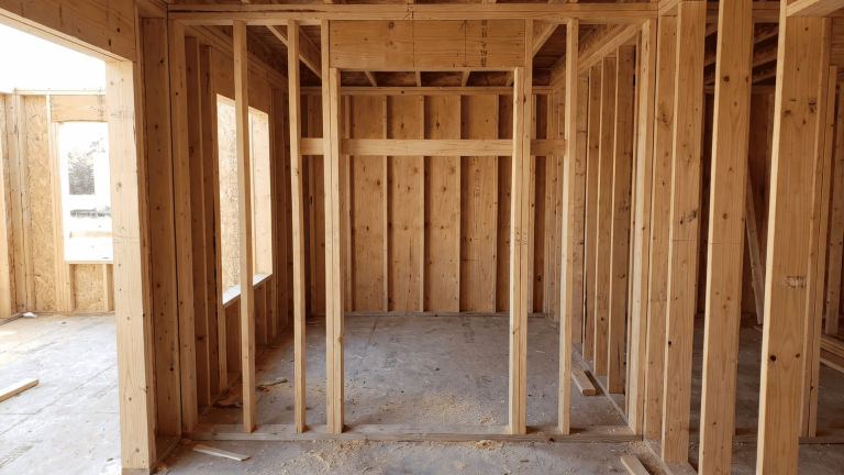 Wood stud wall framing with rough opening sized for a 36 by 80 inch door in a residential build