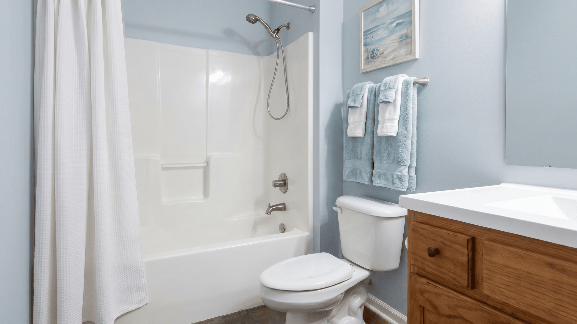 Bathroom with Misty SW 6232 walls, white tub and toilet, wood vanity, and brushed nickel fixtures.