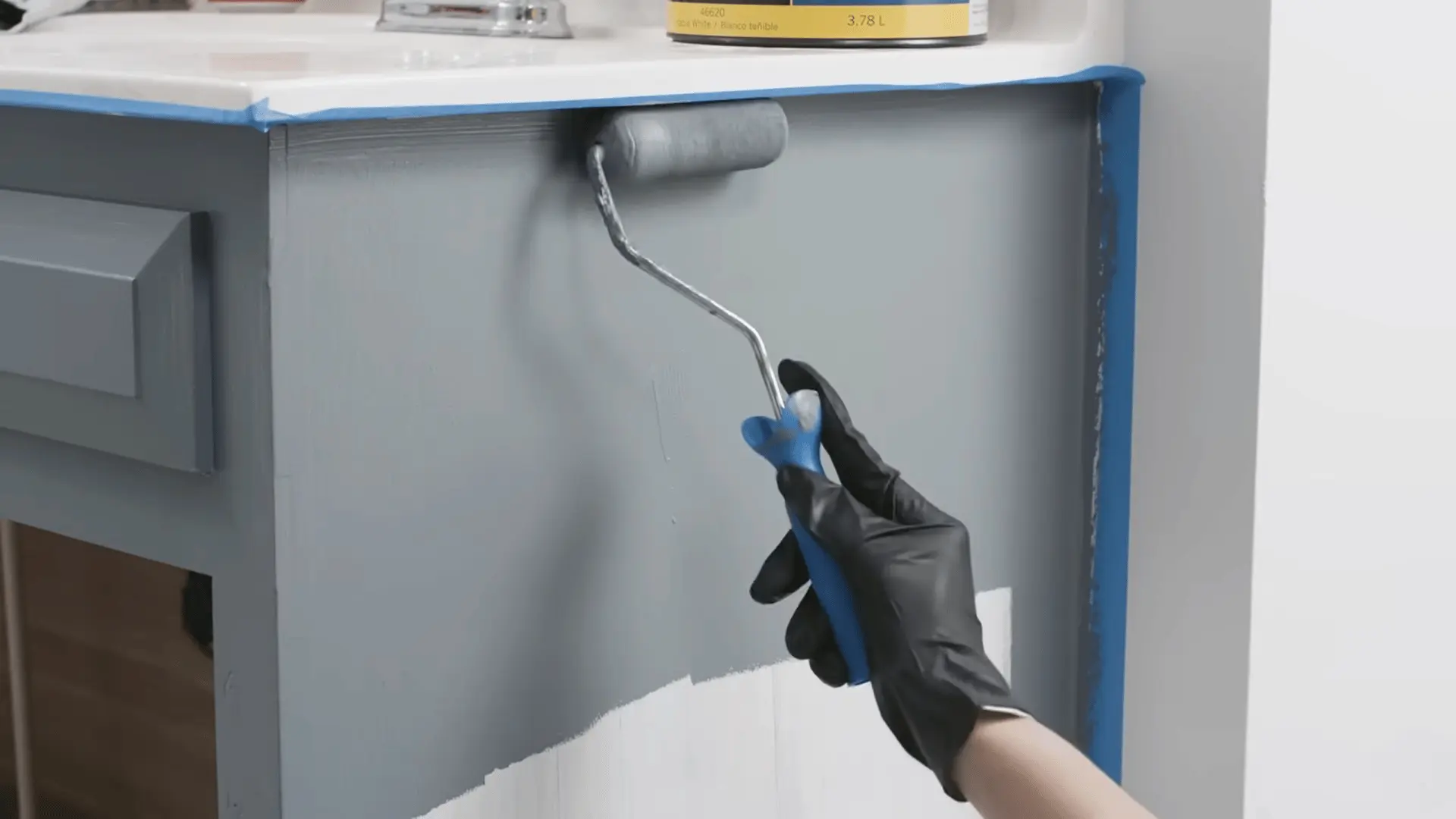 Applying paint to the bathroom vanity using a small roller, ensuring even coverage