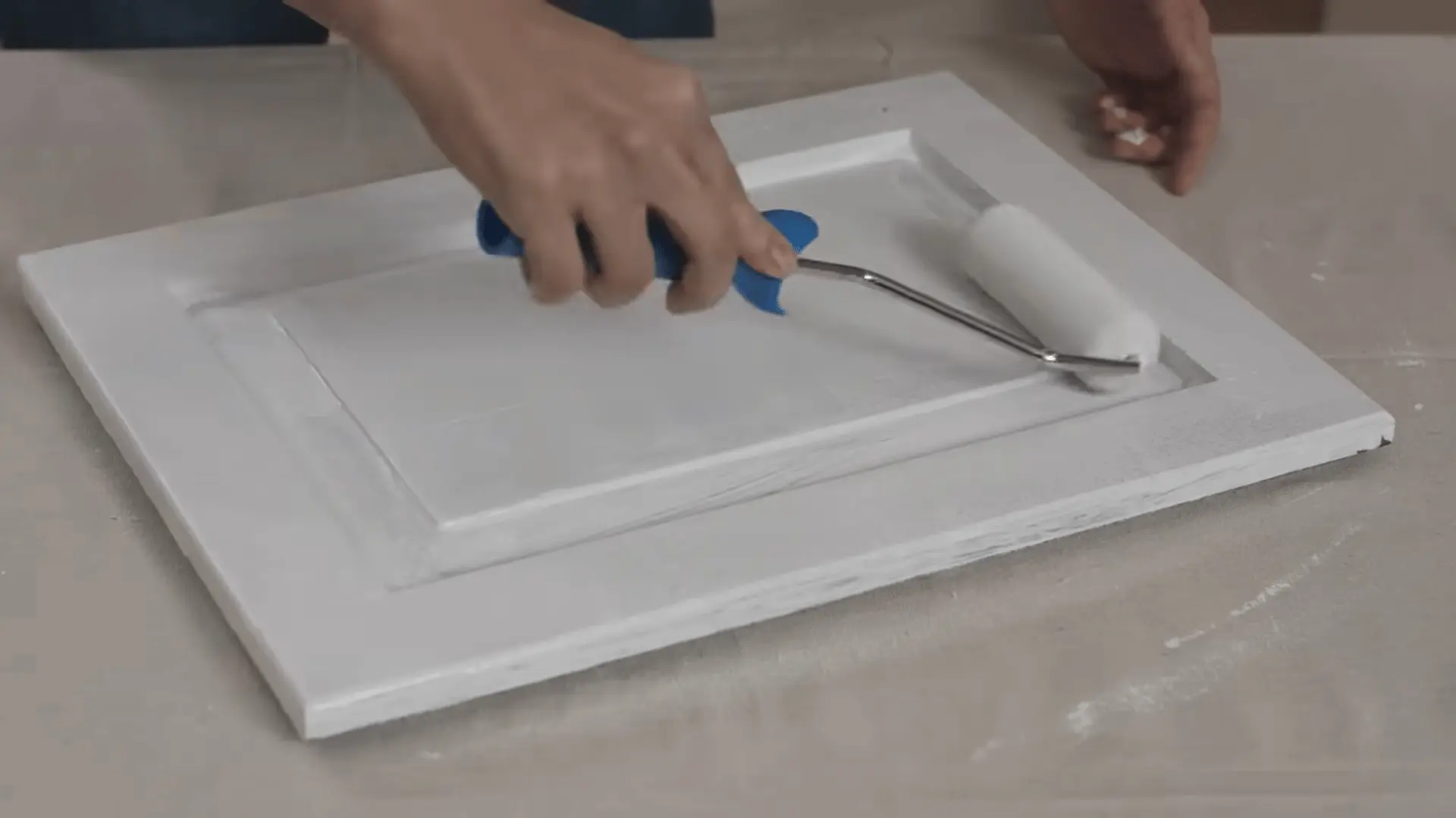 Applying primer to a vanity door with a small paint roller, ensuring even coverage