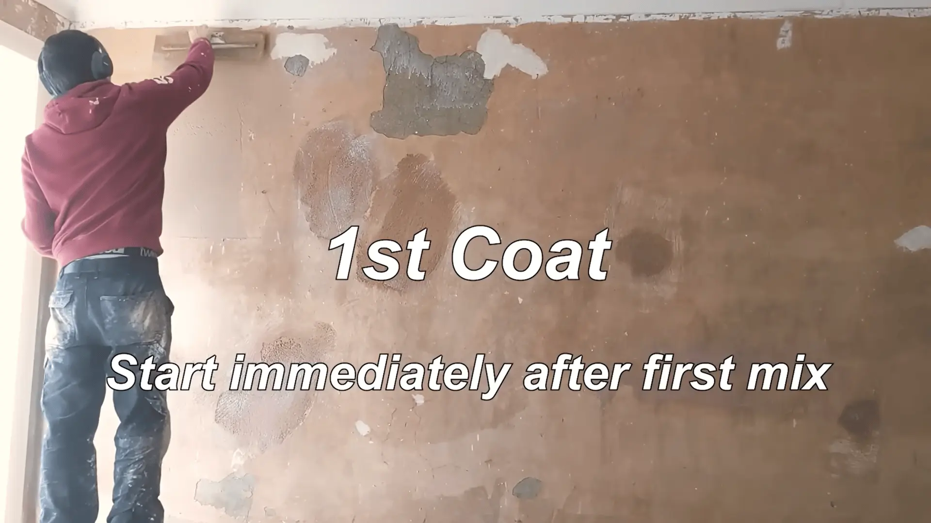 Applying the first coat of plaster to the wall, starting at the top and working down, using consistent pressure with a trowel