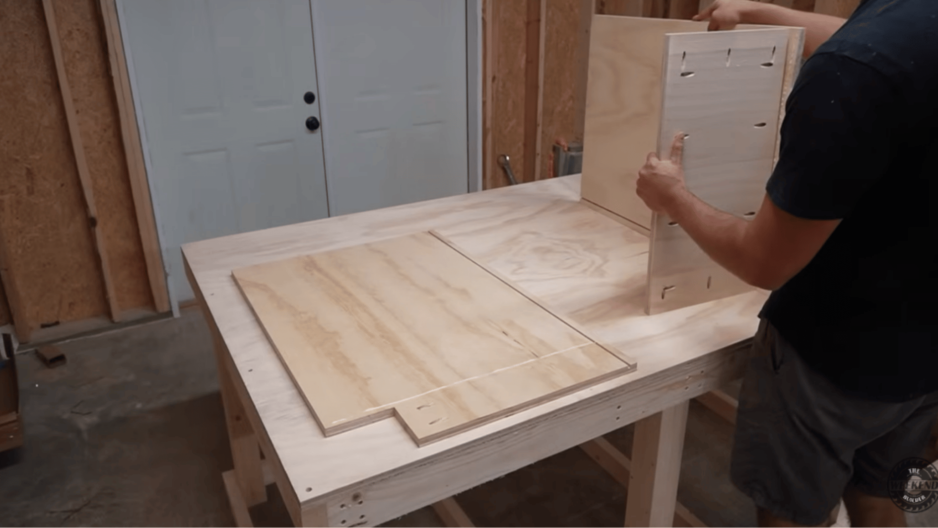 assembling a plywood cabinet box on a workbench using pocket-hole joinery during a diy kitchen cabinet build.