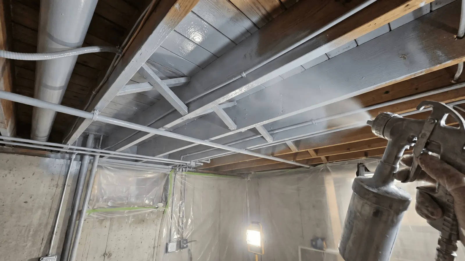 Basement ceiling painted black with visible pipes and ducts blended into surface