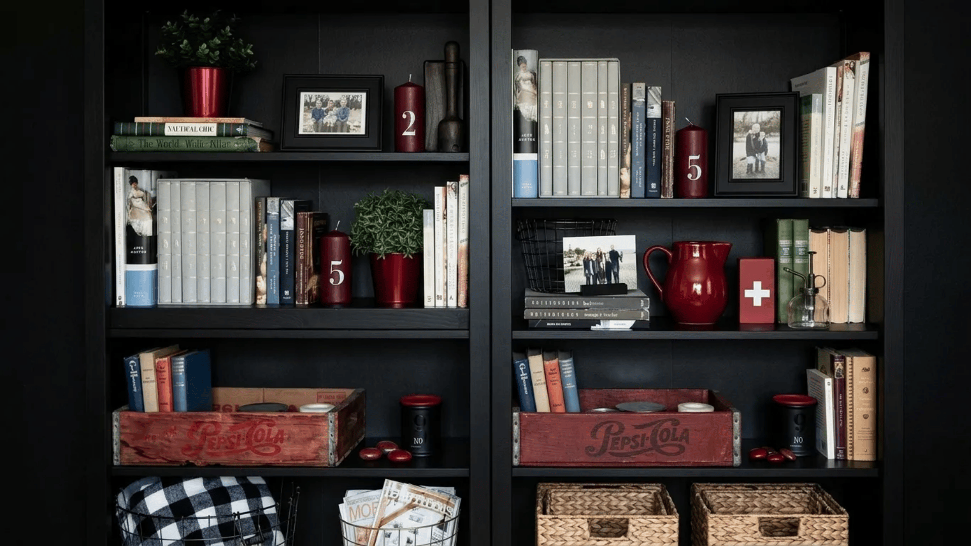 Black bookshelf styled with books, plants, framed photos, candles, and vintage crates, arranged with visual balance and open gaps.
