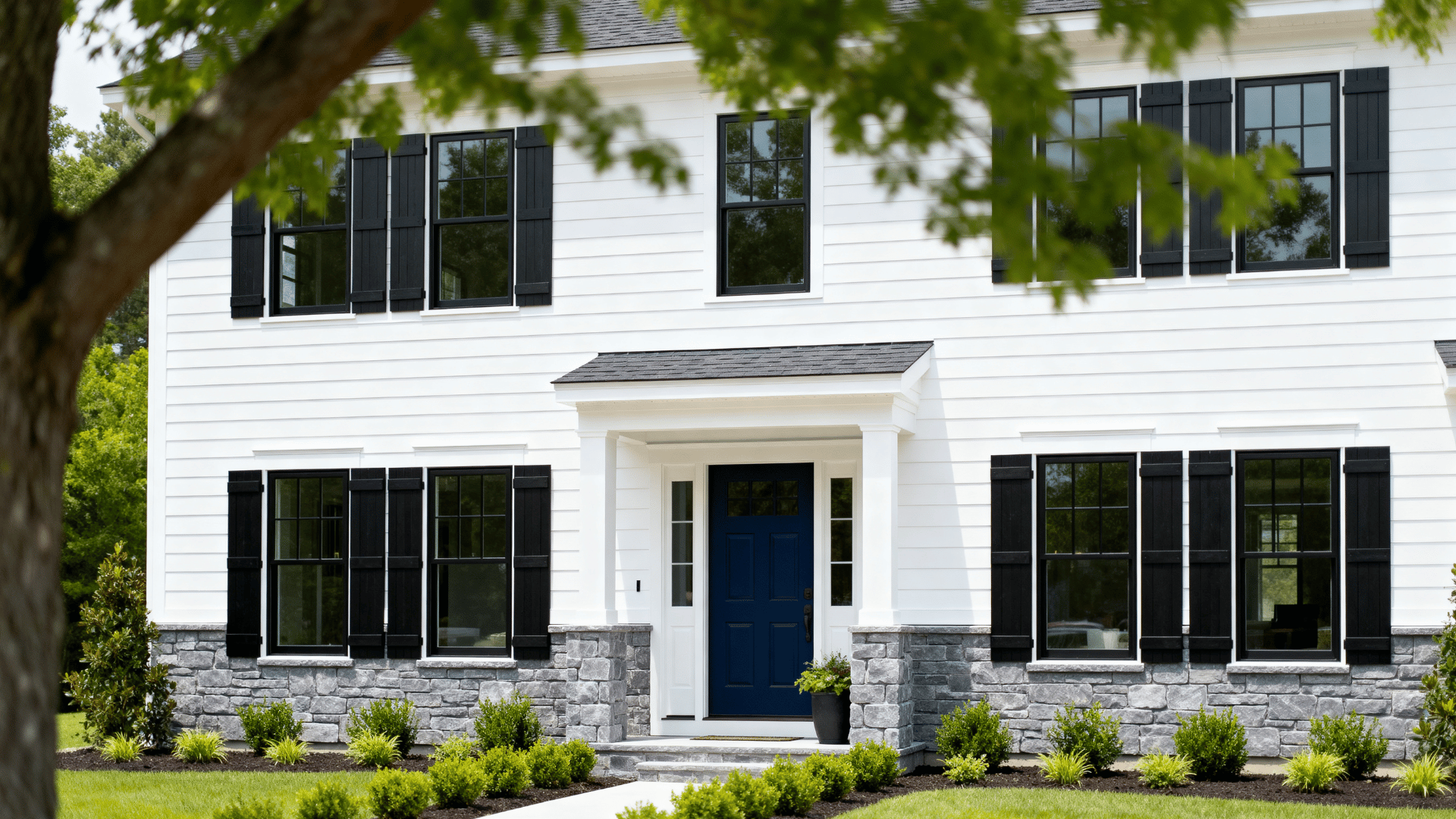 bright white modern farmhouse with navy door, black windows, charcoal shutters, and gray stone accents