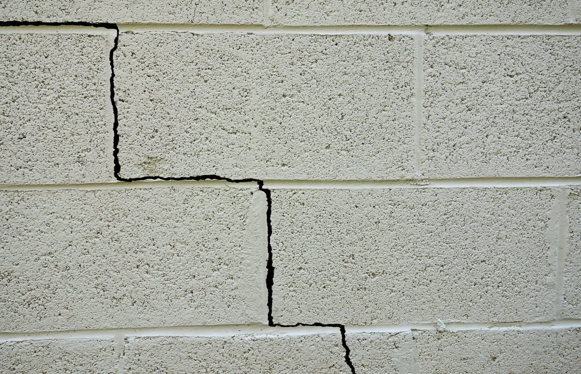 Cracked concrete block wall with visible splits and rough texture
