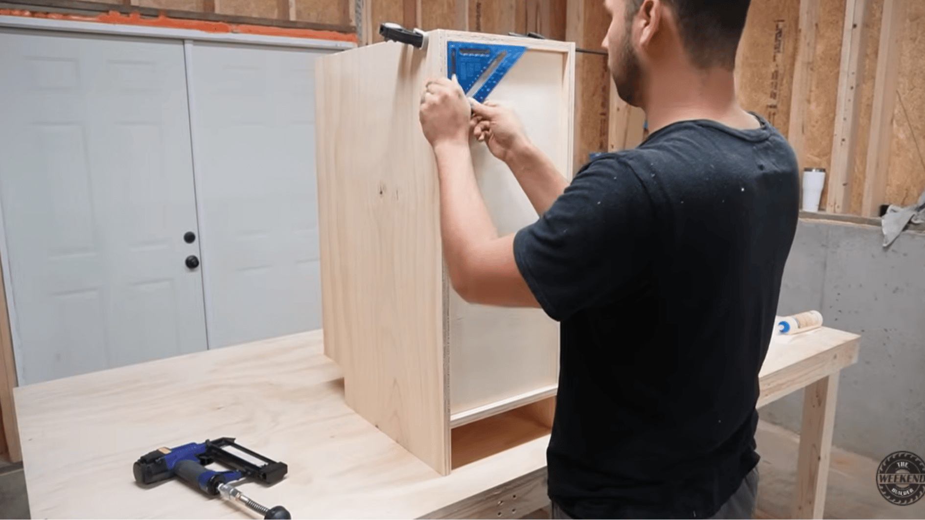 checking cabinet box alignment with a speed square during assembly of a diy kitchen cabinet project.