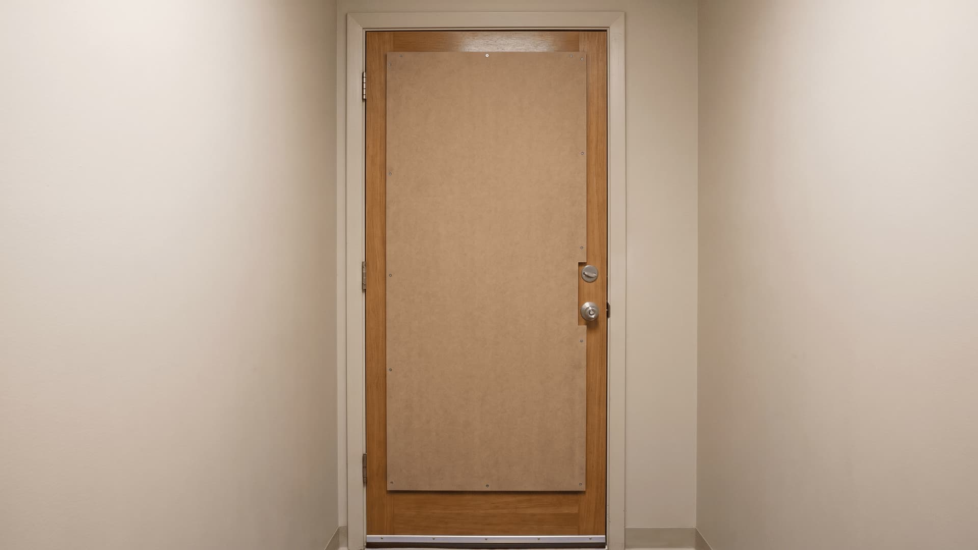 Closed door in a daInterior door with a mounted MDF panel covering the surface to increase weightrk room with slight light visible at edges being checked for remaining gaps